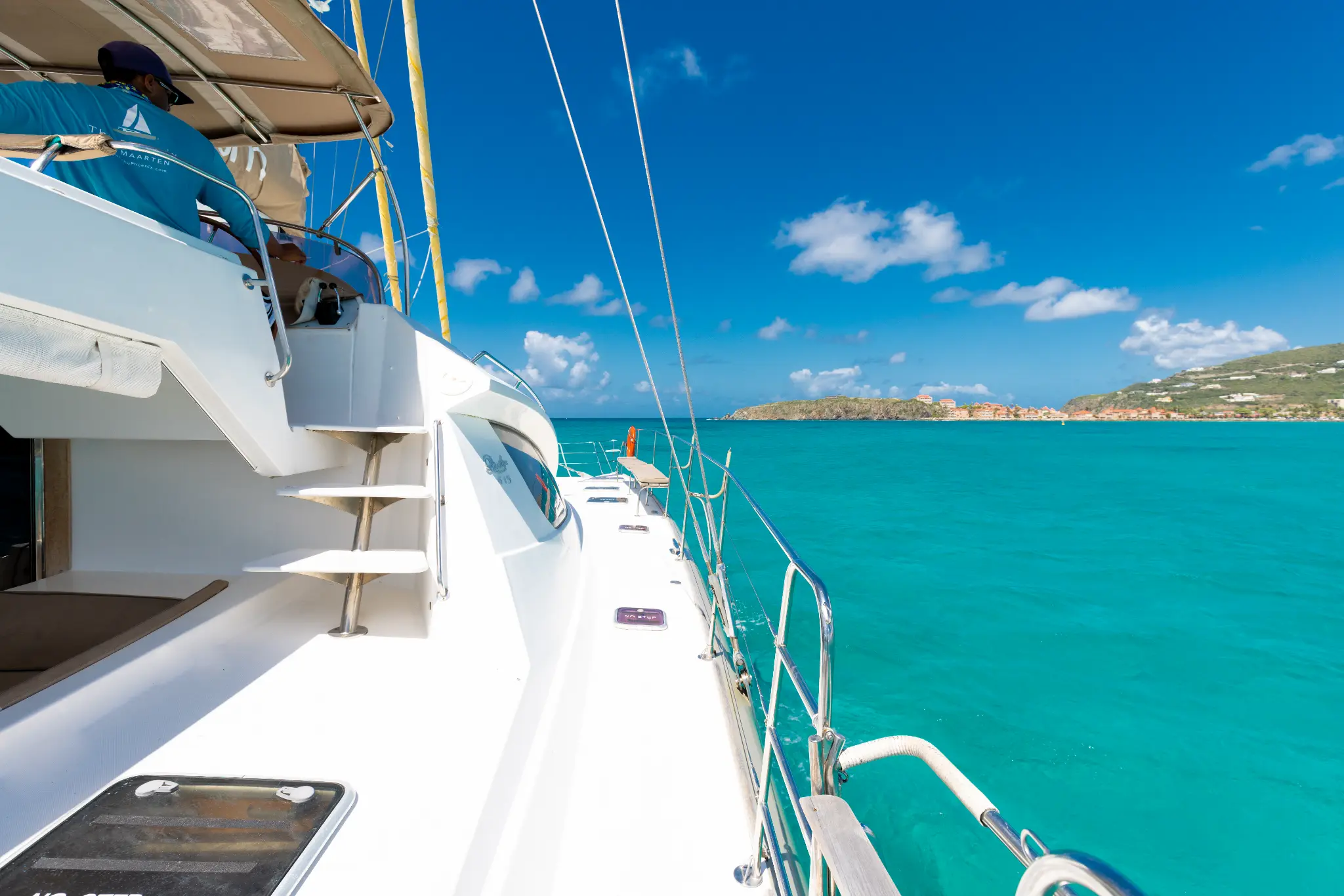 The Phoenix catamaran deck view with turquoise Caribbean water and island in background