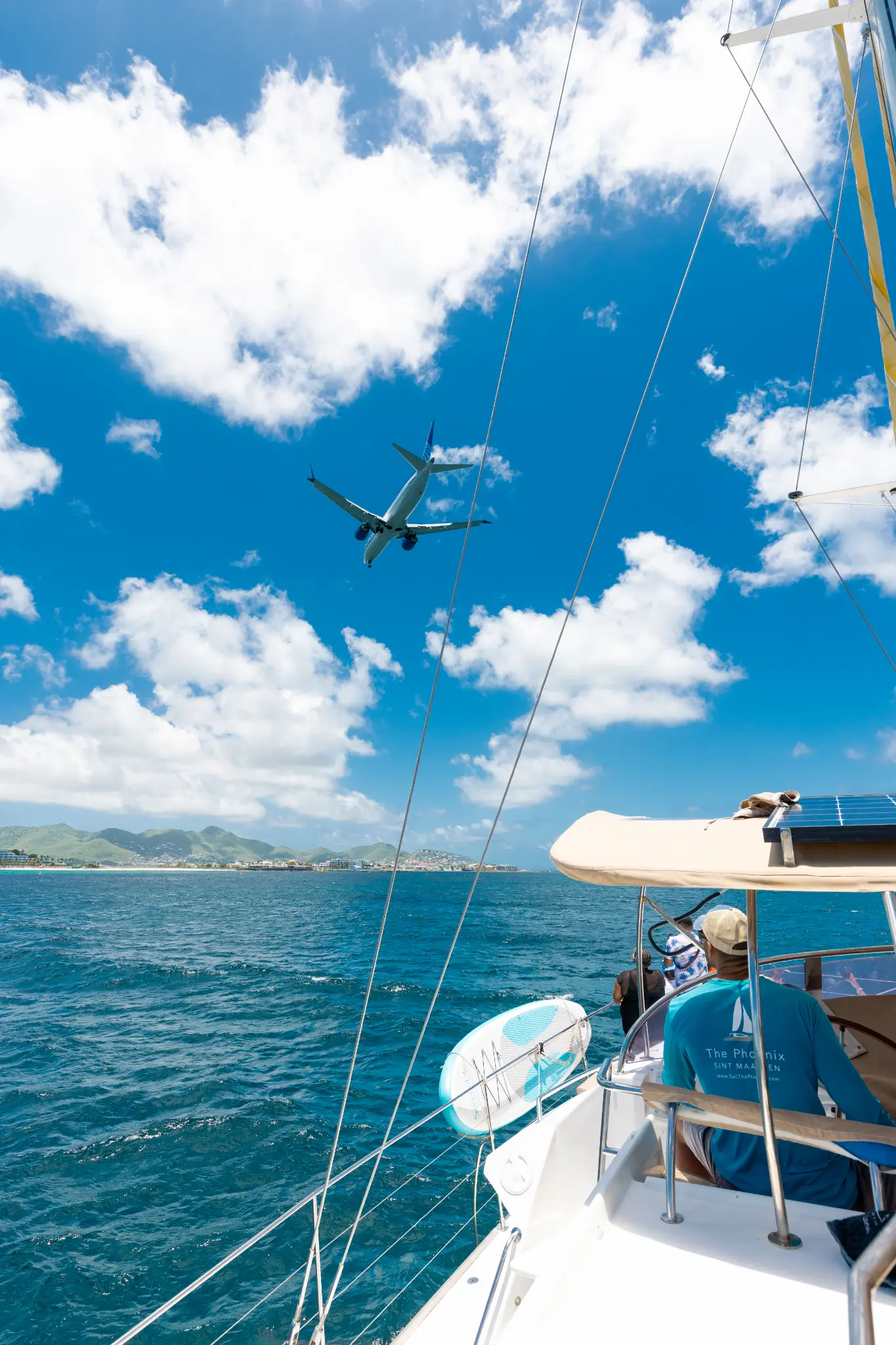 Commercial aircraft flying low over The Phoenix catamaran near St. Maarten airport