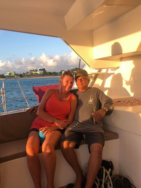 Couple sitting on the aft deck railing of Sail The Phoenix at sunset