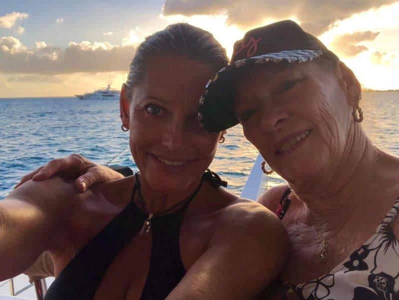 Mother and daughter smiling together on Sail The Phoenix deck with a golden sunset behind