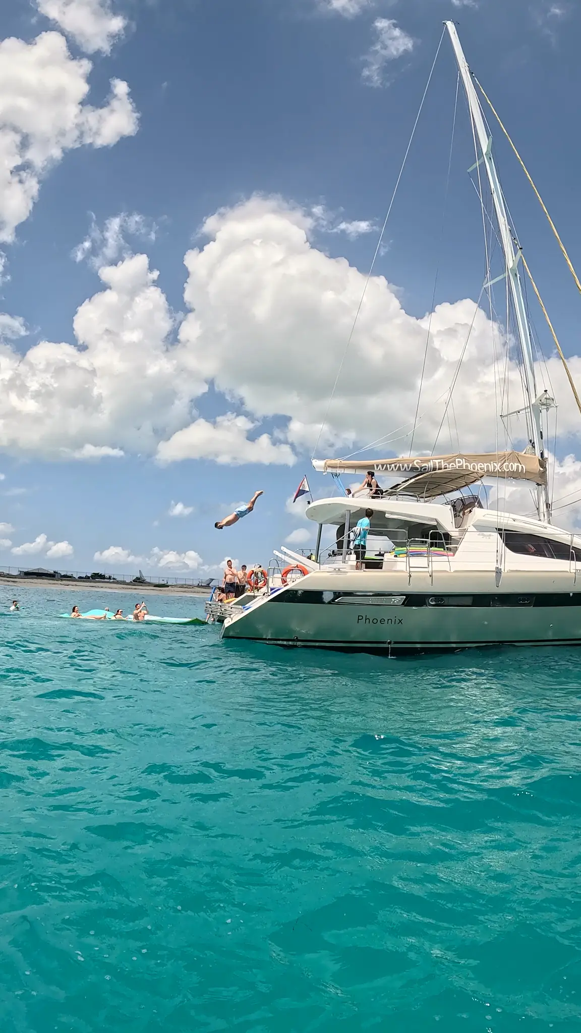 The Phoenix catamaran with guests jumping into turquoise Caribbean water