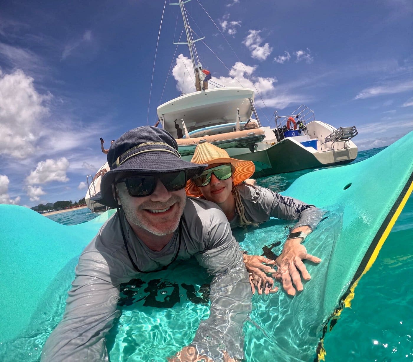 Couple on the floating lily pad with The Phoenix catamaran in the background